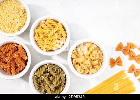 Top view of bowls with assorted uncooked pasta. Mediterranean food. Copy space Stock Photo