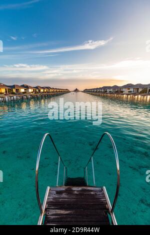 Jetty over swimming atoll and a tropical resort island in Maldives ...
