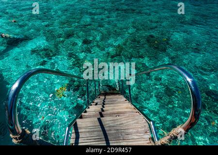 Jetty over swimming atoll and a tropical resort island in Maldives ...