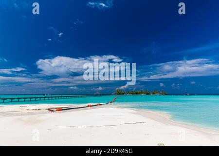 Jetty over swimming atoll and a tropical resort island in Maldives ...