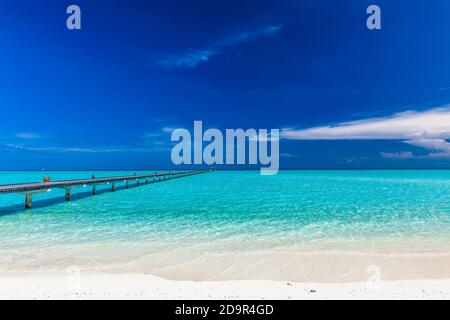 Jetty over swimming atoll and a tropical resort island in Maldives ...