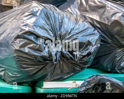 Plastic garbage bags on top of green garbage bins. Stock Photo