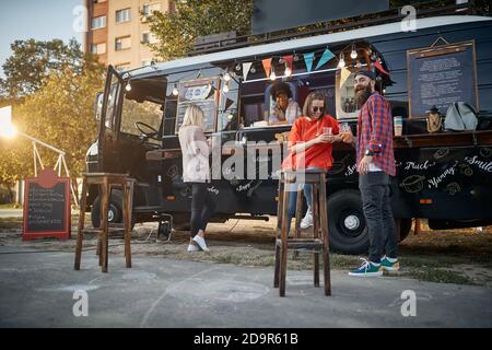 hipster with friends in front of modified truck for mobile fast food service looking at camera Stock Photo