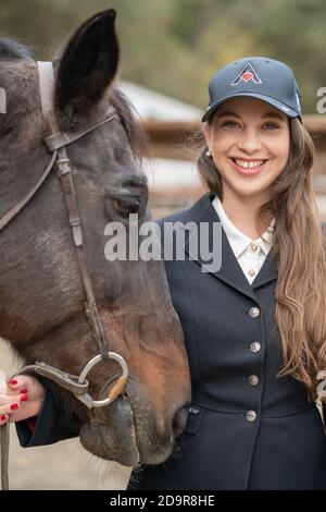 woman in cap petting horse Stock Photo