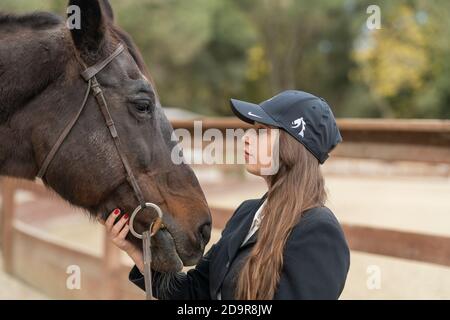 woman in cap petting horse Stock Photo