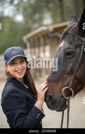 woman in cap petting horse Stock Photo