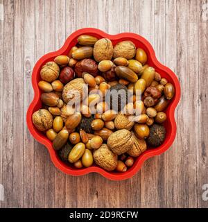 Autumn frame with brown hazelnuts, walnuts, acorns, chestnuts and beechnuts on a wooden background, top view Stock Photo