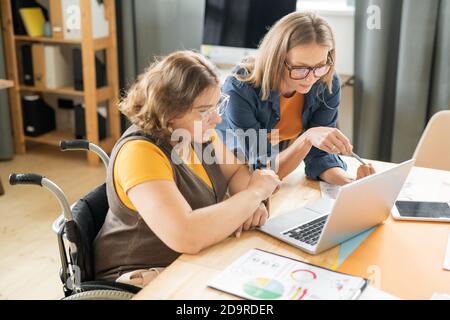 Two young serious female managers or brokers reading data on laptop display Stock Photo