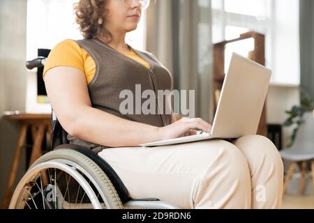 Young contemporary businesswoman of creative designer in wheelchair typing Stock Photo