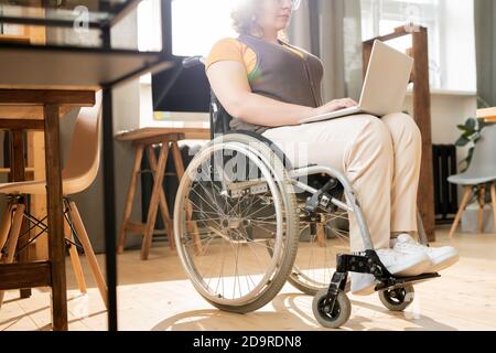 Young disable female office worker looking through text on laptop display Stock Photo