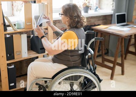 Young disable female office worker in casualwear looking through papers Stock Photo