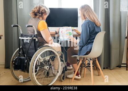 Two young contemporary female office workers discussing financial papers Stock Photo