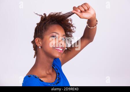 Young African American woman making braids to her frizzy afro hair - Black people Stock Photo