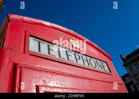 Detail of a red London telephone box. Red phone box lettering and royal crest. In Whitehall, Westminster, London, UK, in bright blue sky autumn day
