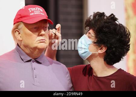 A member of the Madame Tussauds studios team adjusts a wax figure of Donald Trump which has been re-dressed in golf wear following the 2020 US presidential election, after Joe Biden's third bid for the White House has been a success as he is set to become the 46th President of the United States. Stock Photo