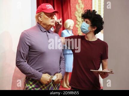 A member of the Madame Tussauds studios team adjusts a wax figure of Donald Trump which has been re-dressed in golf wear following the 2020 US presidential election, after Joe Biden's third bid for the White House has been a success as he is set to become the 46th President of the United States. Stock Photo