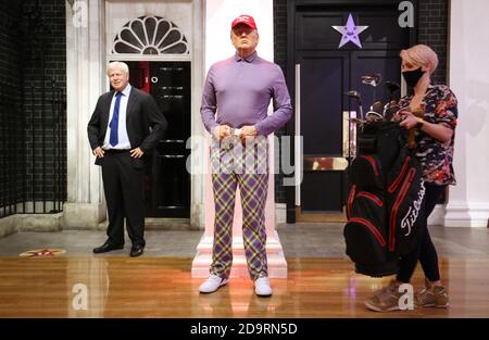 A member of the Madame Tussauds studios team places a set of golf clubs next to a wax figure of Donald Trump which has been re-dressed in golf wear following the 2020 US presidential election, after Joe Biden's third bid for the White House has been a success as he is set to become the 46th President of the United States. Stock Photo