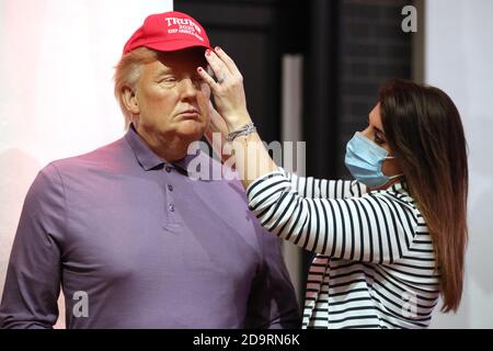 A member of the Madame Tussauds studios team adjusts a wax figure of Donald Trump which has been re-dressed in golf wear following the 2020 US presidential election, after Joe Biden's third bid for the White House has been a success as he is set to become the 46th President of the United States. Stock Photo