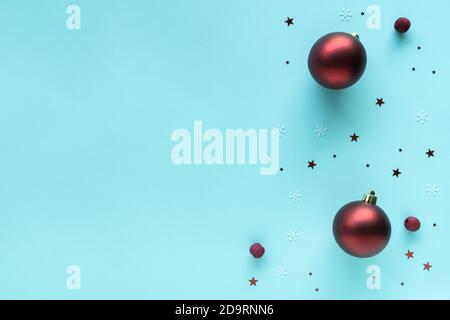 Christmas composition with red bright baubles decorations on pastel blue surface, top view, copy space. Merry Christmas and Happy Holidays greeting Stock Photo