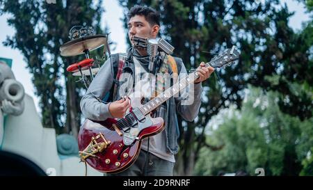 Man Playing Several Instruments at Once Performs in Front of a Fountain ...