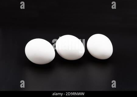 White chicken eggs. Close-up. On a black background. Stock Photo