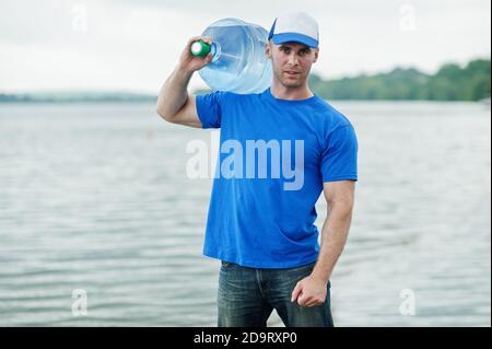 Delivery man carrying water bottle on shoulder. Stock Photo