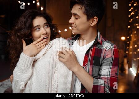 Portrait of a curly amazed woman looking at her boyfriend, have fun together and enjoying New Year holidays moments indoors Stock Photo