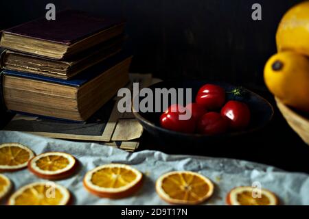 Selective focus on vintage books in soft focus background with tomato, dry oranges, detail of yellow zucchini Stock Photo