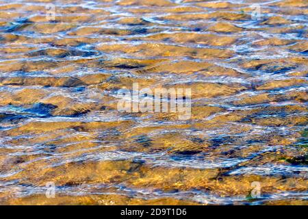 An abstract image of the ripples created by the wind on the water's surface of a rockpool on the beach. Stock Photo