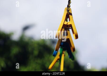 isolated plastic yellow blue and green color clothes clip on a rope Stock Photo