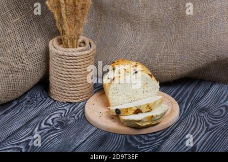 Focaccia bread with olives and sun-dried tomatoes. Nearby is a bouquet of dried grass. On pine boards. Stock Photo