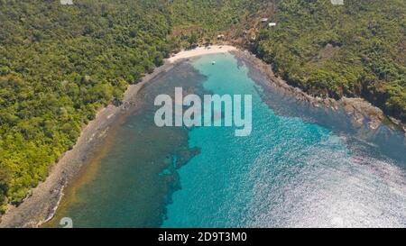 Sea bay with turquoise water and a small white beach.Coast of the island of Camiguin, Philippines.Beautiful lagoon and volcanic island covered with dense forest, view from above. Stock Photo