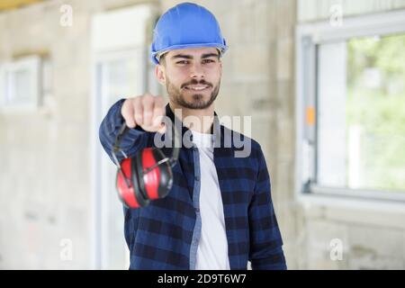 young male worker offering earmuffs Stock Photo