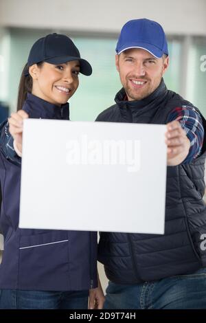 portrait of smiling workers holding blank billboard Stock Photo
