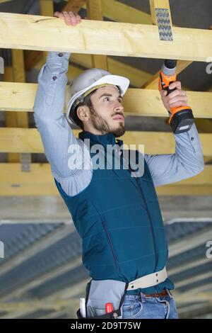 carpenter in construction helmet fix clapboard on ceiling Stock Photo