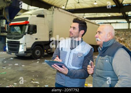 two male workers with clipboard in recycling center Stock Photo