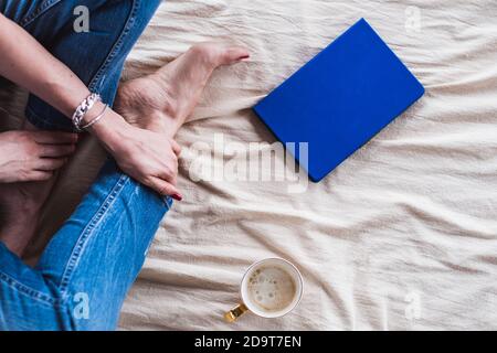 Girl sitting on the floor on a blanket with a mug of coffee and a notepad, top view. The girl writes down her ideas Stock Photo
