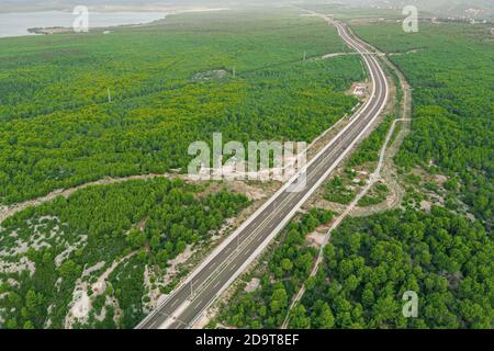 View of the highway car road through green forest from above, travel adventure concept Stock Photo