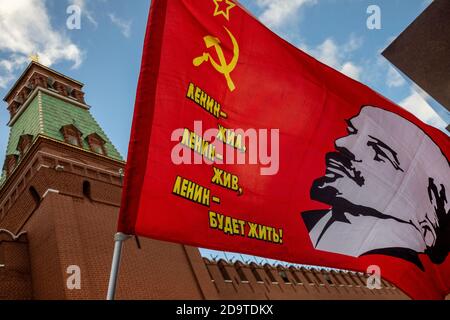 Red flag with a portrait of the revolution leader Vladimir Lenin and the inscription 'Lenin Lived, Lenin Lives, and Lenin Will Always Live' on the background of the Senate tower of the Moscow Kremlin in the center of Moscow, Russia Stock Photo
