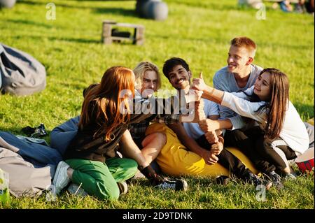 Young multi ethnic group of people watching movie at poof in open air cinema. Stock Photo