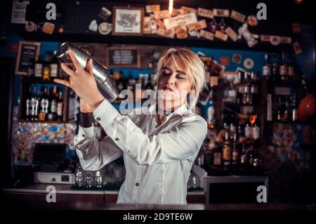 Focused woman bartender intensely finishes his creation in pub Stock Photo