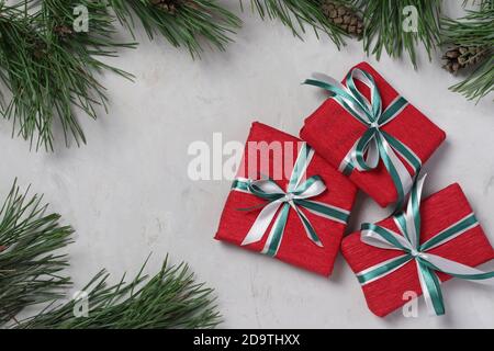 Three Christmas gifts in red paper with green and white ribbons on gray background. Xmas holiday presents. Flat lay. Boxing day. Top view Stock Photo