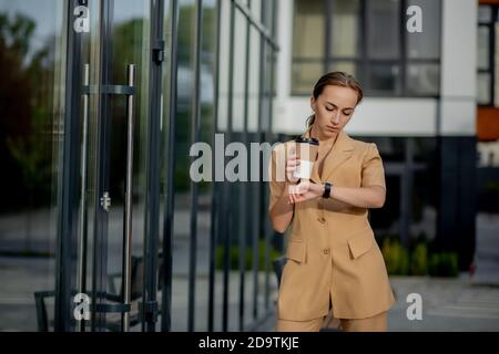 Caucasian woman with smartphone standing against street building background. Stock Photo