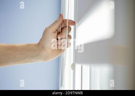 Man testing cassette roller blinds on windows. Stock Photo