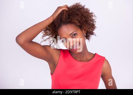 Young African American woman making braids to her frizzy afro hair - Black people Stock Photo