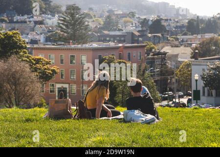 San Francisco, California, USA - MARCH 15 2019: Couple relaxing on a picnic in Alamo Square Park on a sunny day