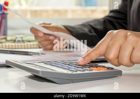 The businessman's hand is pressing a calculator, doing finance work and calculating on the table about expenses at home office. Stock Photo