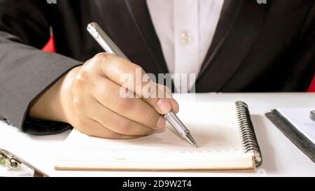 A woman who uses a pen to write wooden desk notebooks and memos. Stock Photo