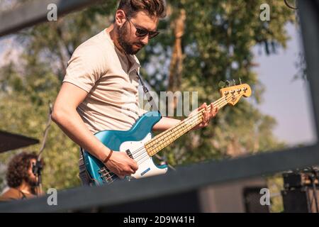 Bass player on the move while playing on stage at the concert Stock Photo