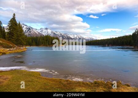 Scenic Landscape view Frozen Johnson Lake Ice Covered Water Surface Rocky Mountain Peaks Horizon, Banff National Park Canada Stock Photo